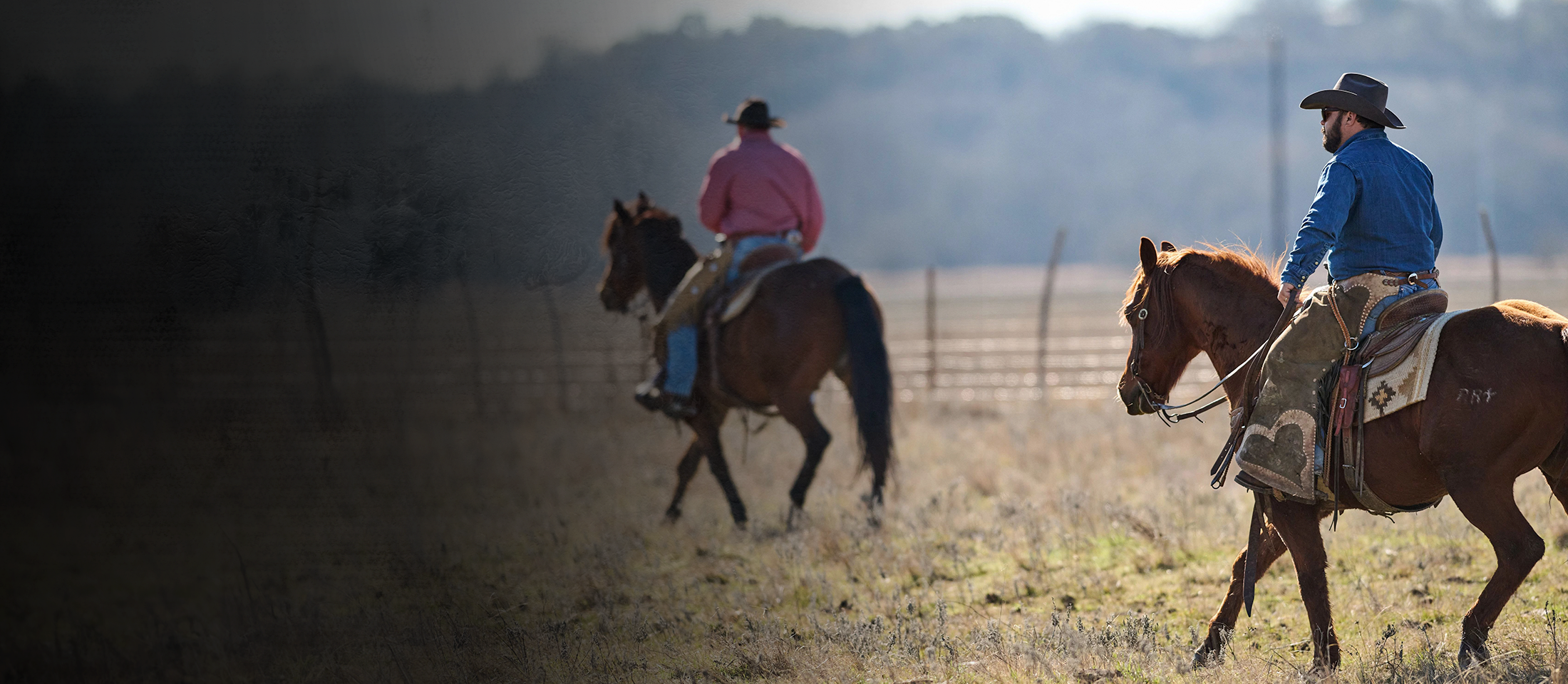 Dos vaqueros montando a caballo con botas Doble-H.